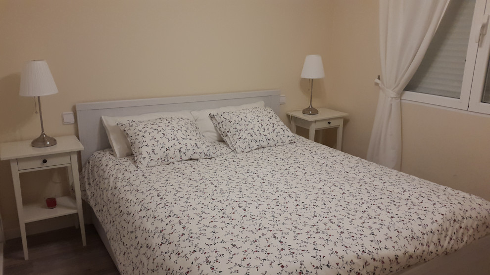 Imagen de dormitorio principal minimalista de tamaño medio sin chimenea con paredes amarillas, suelo laminado y suelo marrón