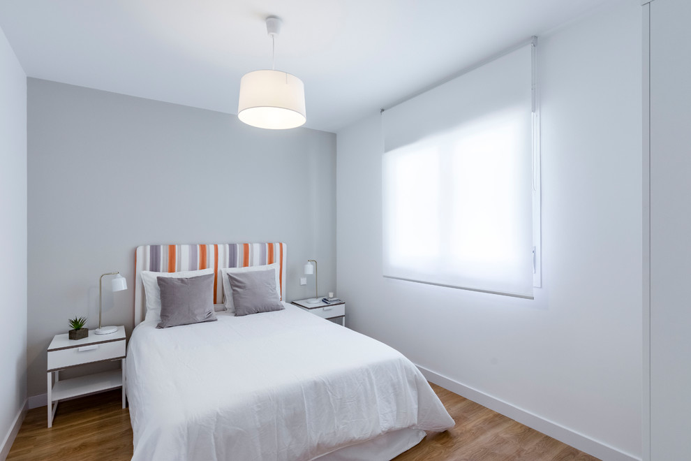 Imagen de habitación de invitados nórdica pequeña con paredes grises, suelo de madera en tonos medios y suelo marrón