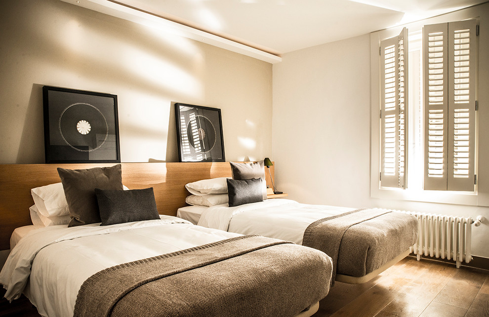 Design ideas for a large classic guest bedroom in Madrid with white walls, medium hardwood flooring and brown floors.