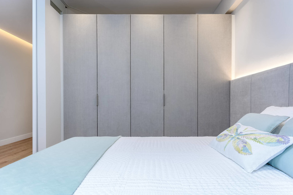 Diseño de dormitorio principal actual con paredes blancas y suelo de madera en tonos medios