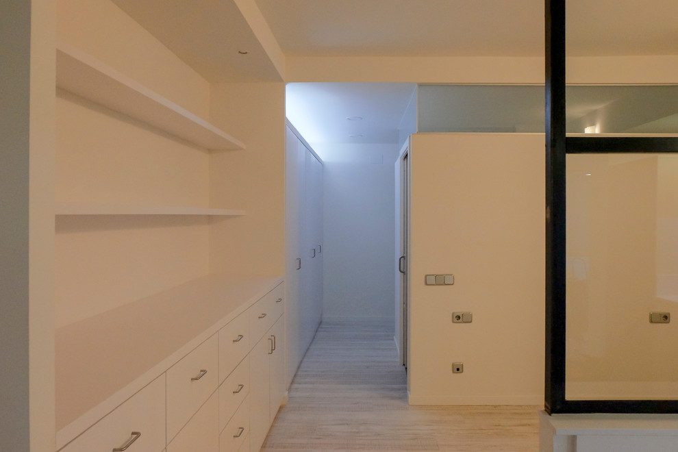 Modelo de dormitorio tipo loft nórdico de tamaño medio con paredes blancas y suelo laminado