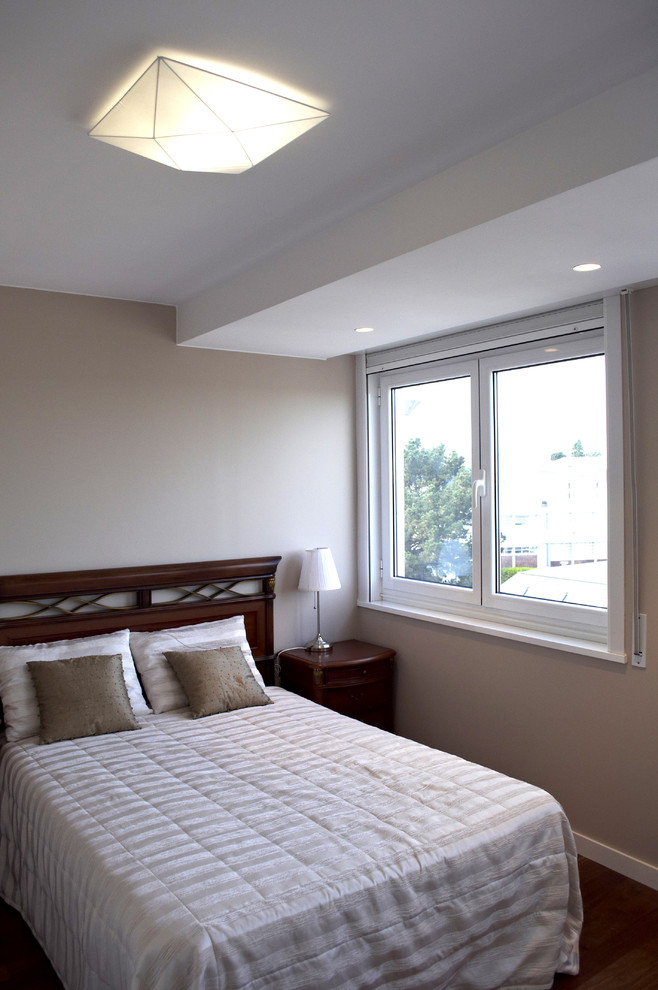 Modelo de dormitorio principal tradicional renovado pequeño sin chimenea con paredes beige y suelo de madera oscura
