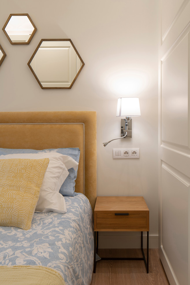Imagen de dormitorio contemporáneo de tamaño medio sin chimenea con paredes blancas, suelo laminado y suelo marrón