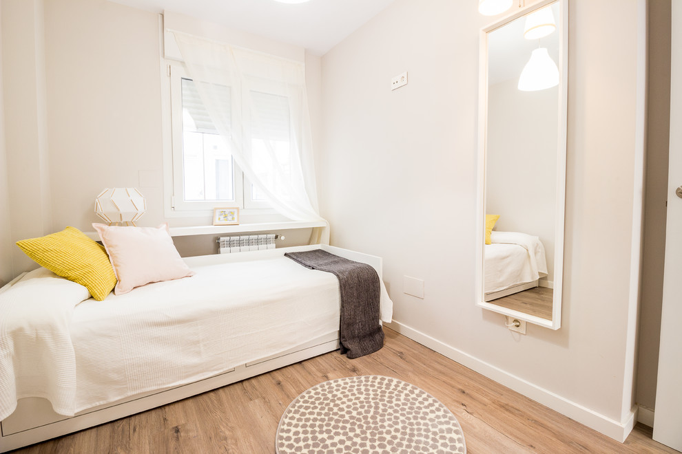 Ejemplo de habitación de invitados actual pequeña con suelo laminado, paredes beige y suelo beige