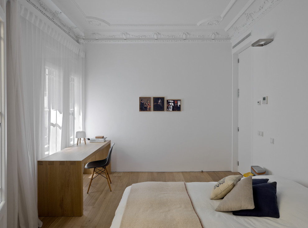 Ejemplo de habitación de invitados minimalista con paredes blancas y suelo de madera en tonos medios