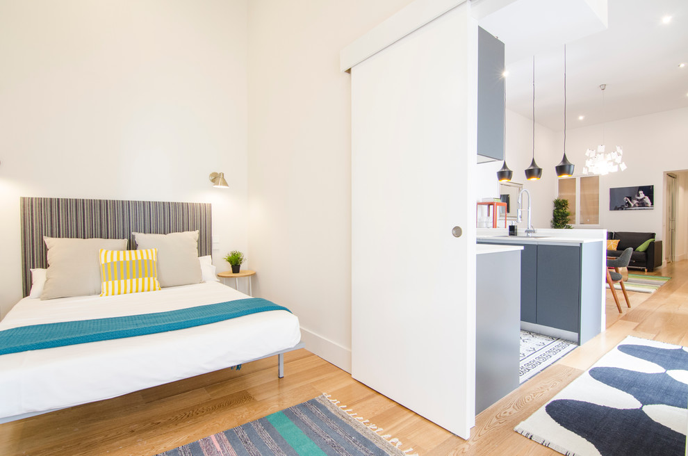 Imagen de dormitorio principal actual de tamaño medio sin chimenea con paredes blancas y suelo de madera en tonos medios