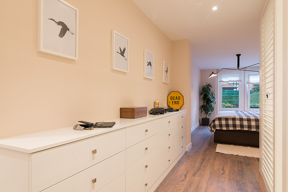 Modelo de dormitorio principal clásico renovado con paredes beige, suelo de madera en tonos medios y suelo marrón