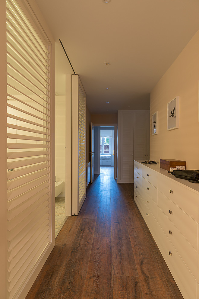 Modelo de dormitorio principal clásico renovado con paredes beige, suelo de madera en tonos medios y suelo marrón