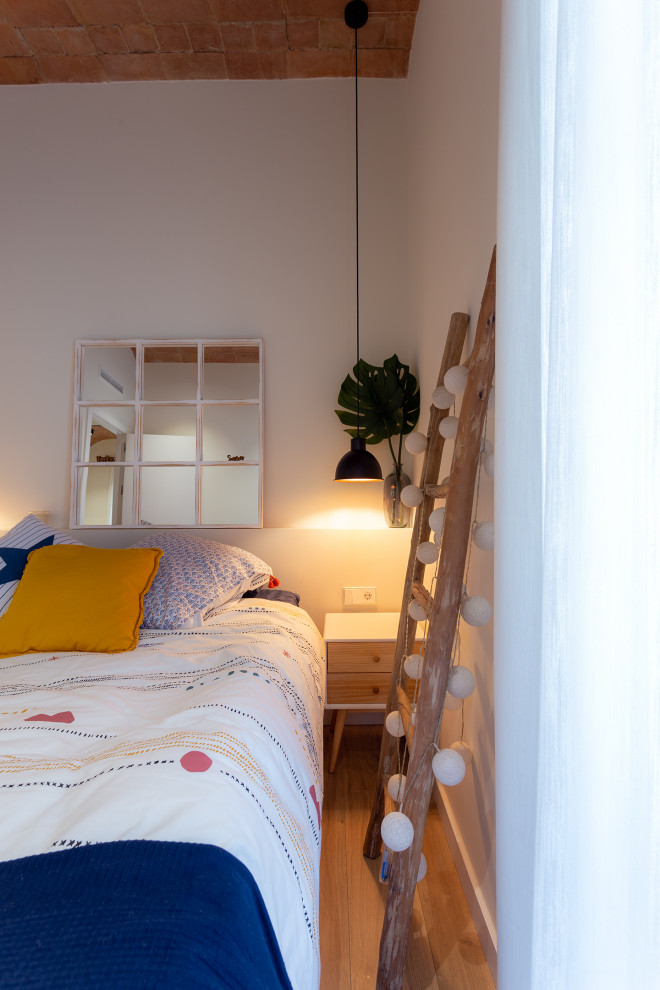 Imagen de dormitorio principal y abovedado costero de tamaño medio sin chimenea con paredes blancas, suelo de madera en tonos medios y suelo marrón