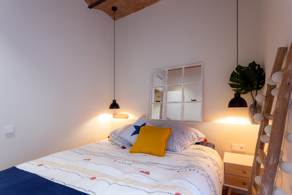 Ejemplo de dormitorio principal y abovedado marinero de tamaño medio sin chimenea con paredes blancas, suelo de madera en tonos medios y suelo marrón