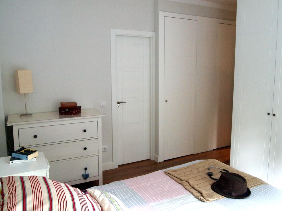 Modelo de dormitorio principal tradicional renovado pequeño con suelo laminado, suelo marrón y paredes grises