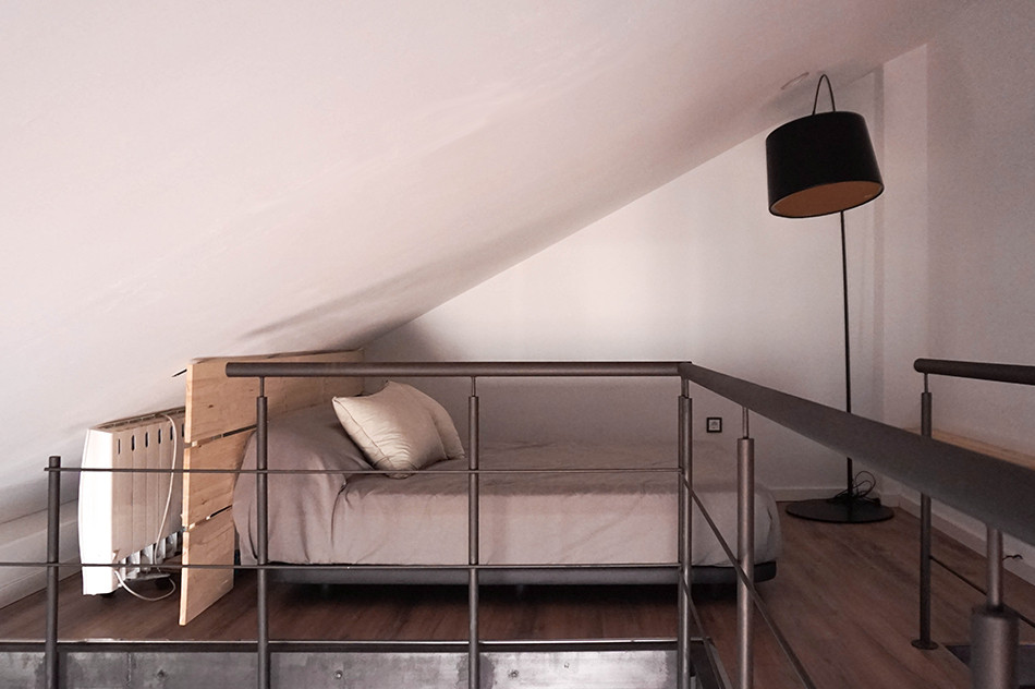 Ispirazione per una camera da letto stile loft industriale di medie dimensioni con pareti bianche, pavimento in laminato e pavimento marrone