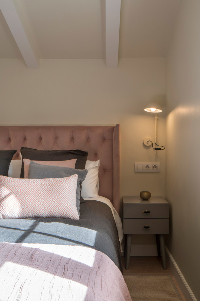 Modelo de dormitorio tradicional renovado grande con paredes beige, suelo laminado y suelo rosa