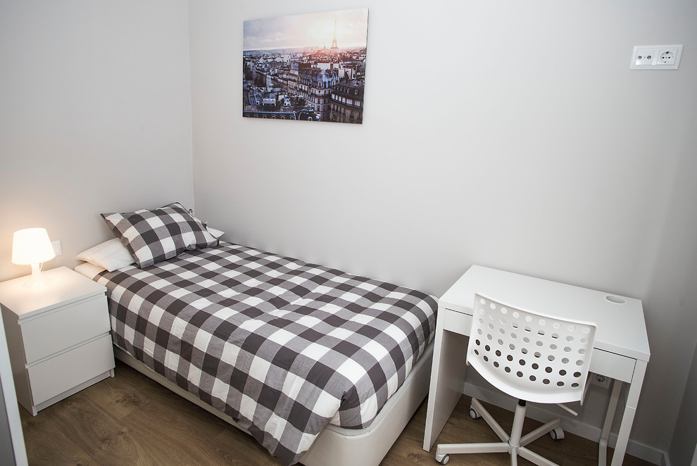 Modelo de dormitorio actual de tamaño medio sin chimenea con paredes grises, suelo de madera en tonos medios y suelo marrón