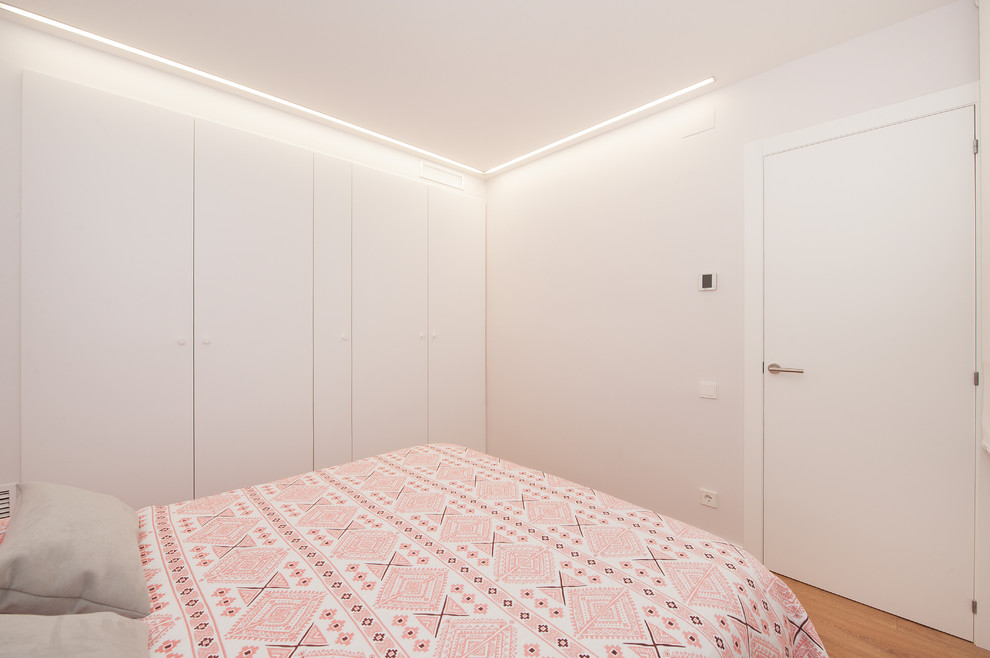 Photo of a medium sized modern master bedroom in Barcelona with white walls, medium hardwood flooring, no fireplace and brown floors.