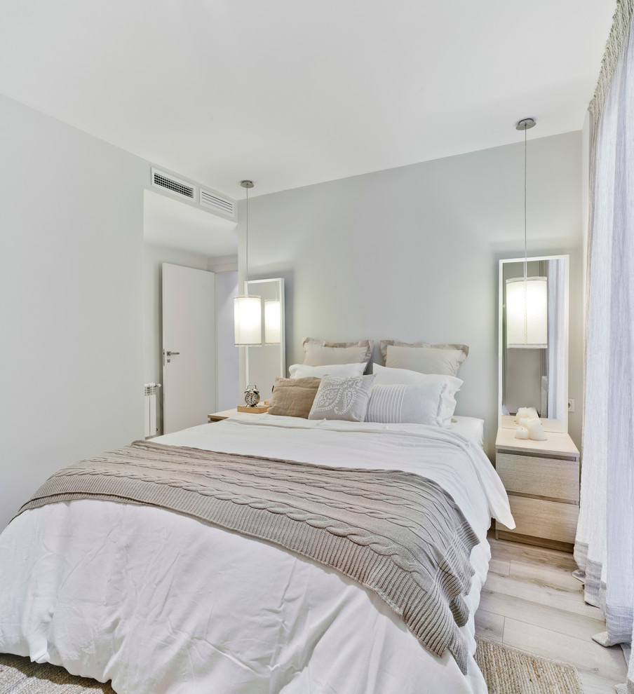 Ejemplo de dormitorio principal contemporáneo de tamaño medio sin chimenea con paredes blancas y suelo de madera clara