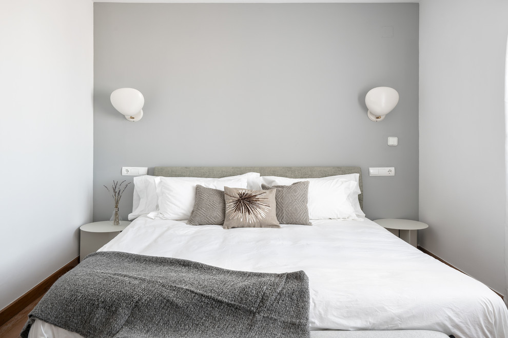 Cette photo montre une chambre d'amis moderne de taille moyenne avec un mur gris, parquet foncé et un sol marron.