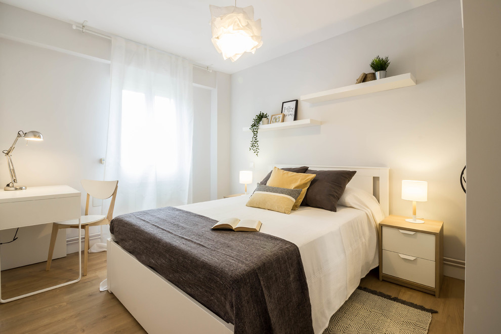Diseño de dormitorio principal escandinavo sin chimenea con paredes grises, suelo marrón y suelo laminado