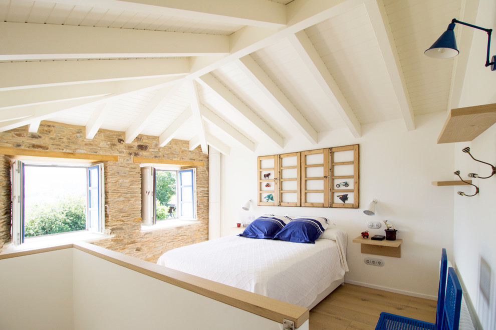 Imagen de dormitorio mediterráneo con paredes blancas, suelo de madera en tonos medios y suelo marrón