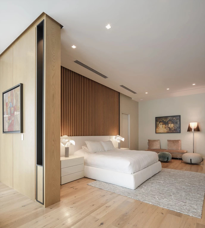 Réalisation d'une grande chambre parentale minimaliste avec un mur beige, un sol en bois brun et un sol marron.