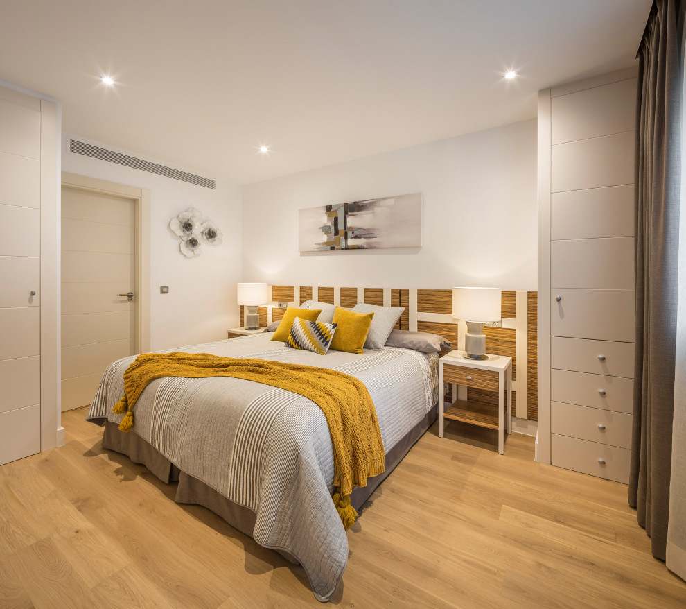 Foto di una grande camera da letto stile loft contemporanea con pareti beige, pavimento in legno massello medio e carta da parati