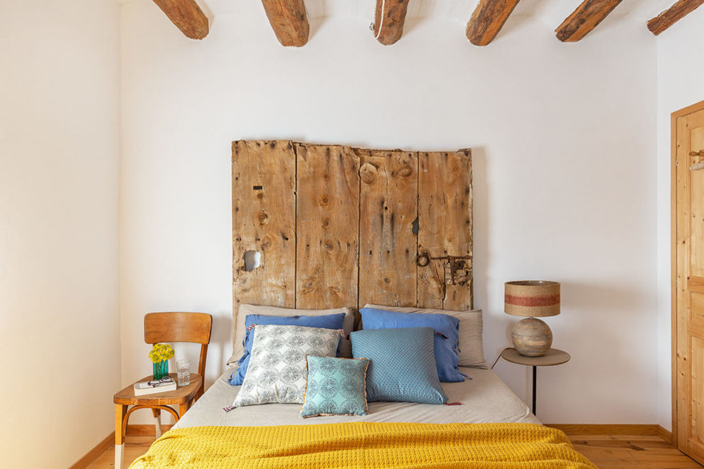 Idée de décoration pour une grande chambre méditerranéenne avec un mur blanc, un sol en bois brun et un sol marron.