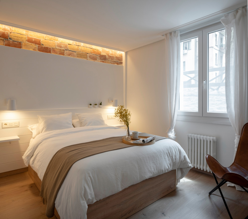 Modern inredning av ett sovrum, med vita väggar, ljust trägolv och beiget golv