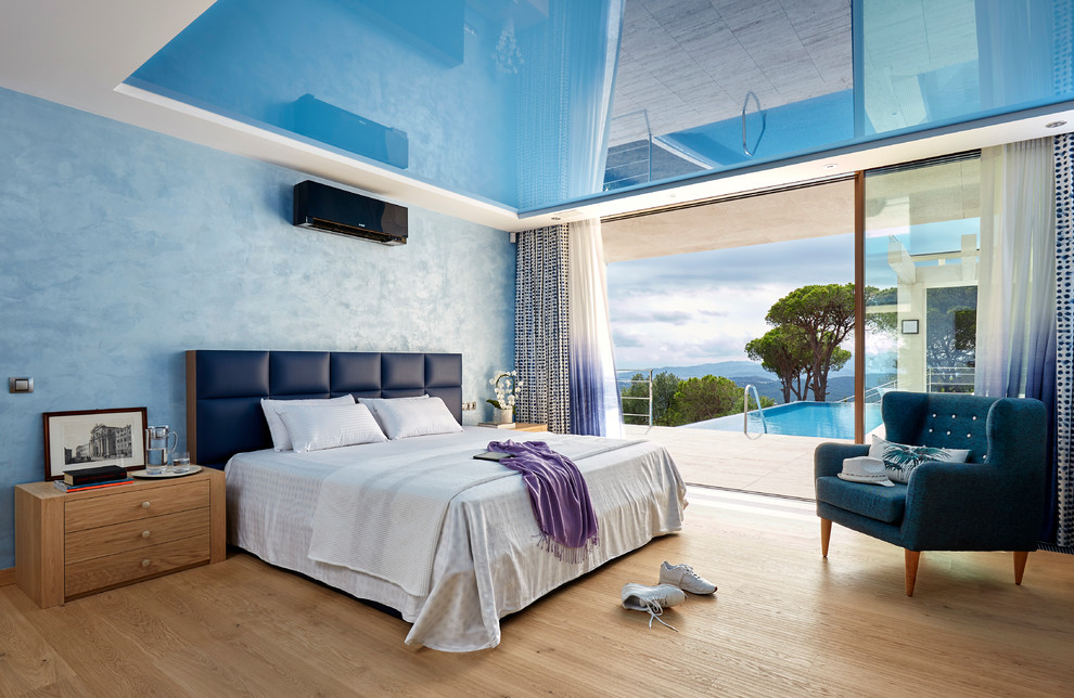 Imagen de dormitorio principal contemporáneo grande sin chimenea con paredes azules y suelo de madera en tonos medios