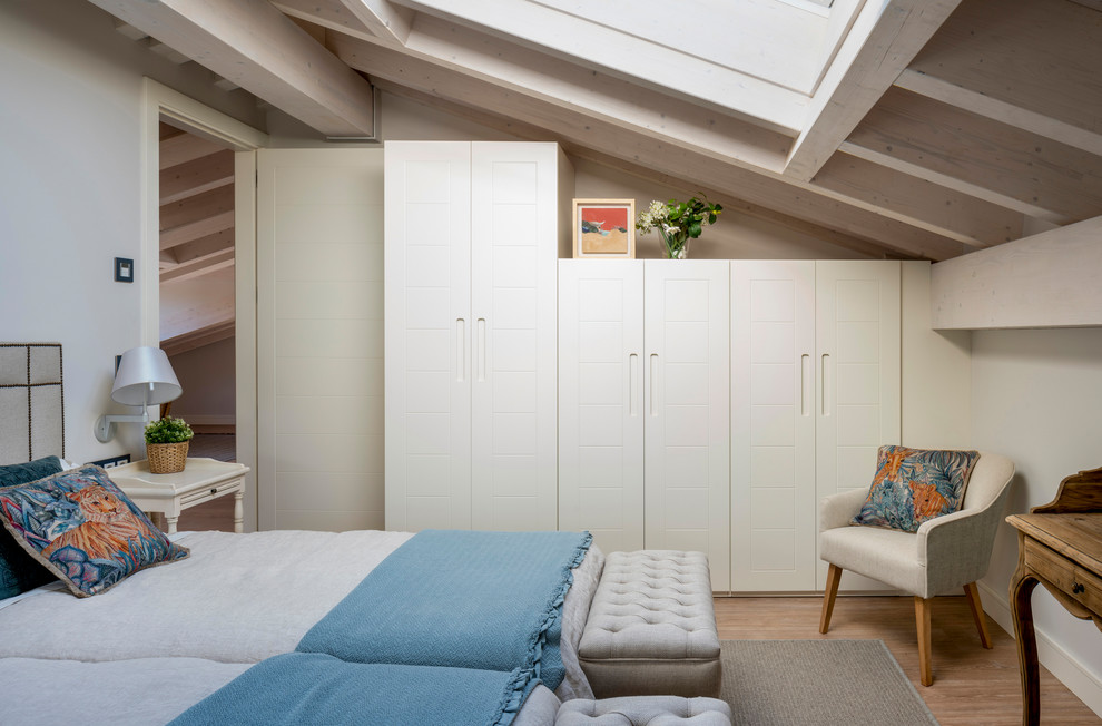 Ejemplo de habitación de invitados clásica renovada de tamaño medio sin chimenea con paredes beige, suelo laminado y suelo marrón