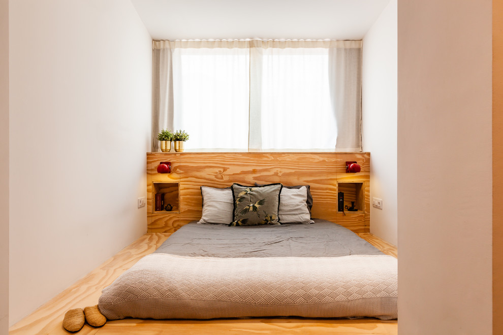 Imagen de dormitorio actual con paredes blancas, suelo de contrachapado y suelo marrón