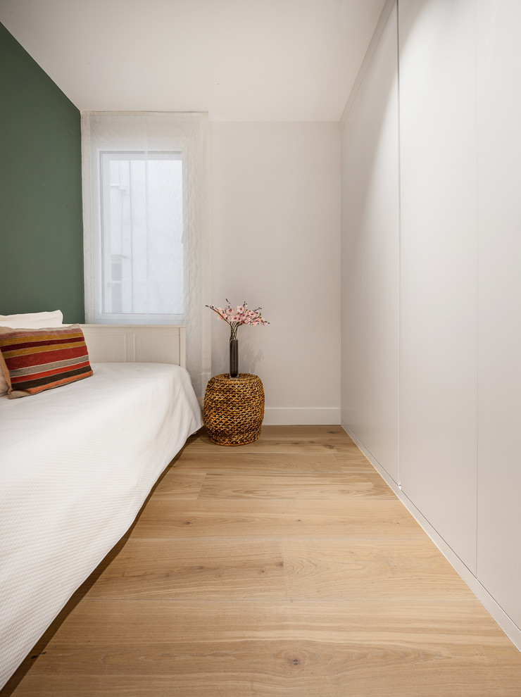 Foto de habitación de invitados contemporánea pequeña sin chimenea con paredes blancas y suelo de madera en tonos medios