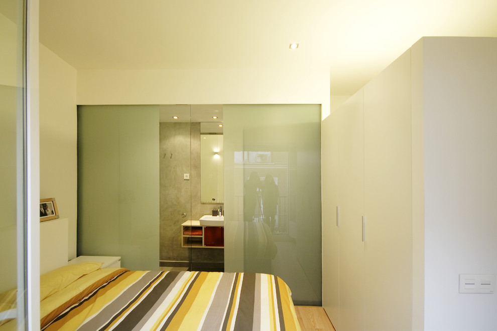 Foto di una camera da letto stile loft minimalista di medie dimensioni con pareti bianche e parquet chiaro