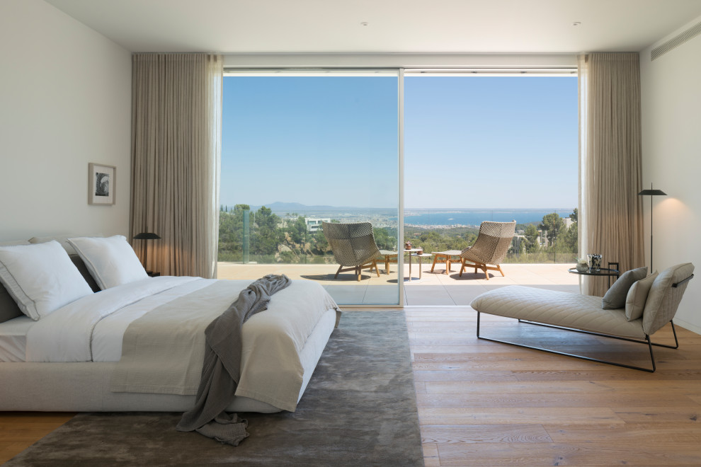 Imagen de dormitorio moderno con paredes blancas, suelo de madera en tonos medios y suelo marrón