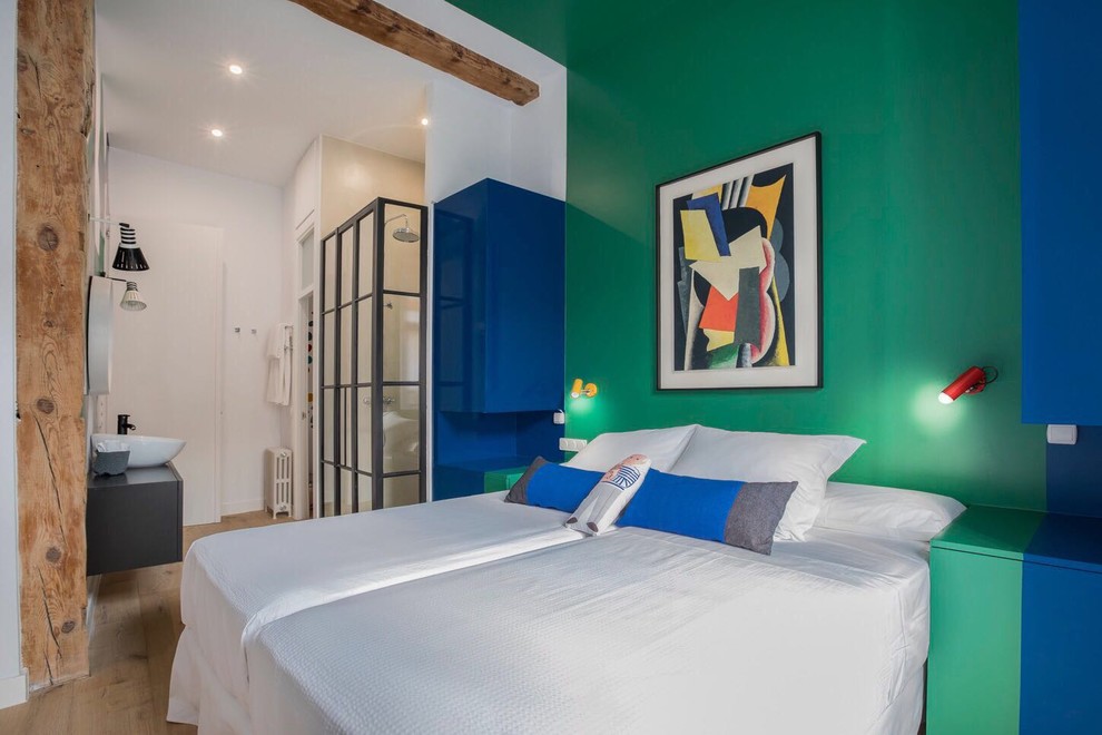 Modelo de dormitorio ecléctico con paredes verdes y suelo de madera en tonos medios