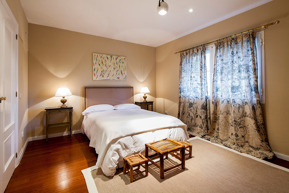 Modelo de dormitorio principal clásico renovado grande sin chimenea con paredes beige y suelo de madera oscura