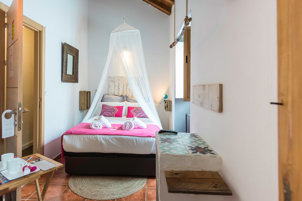 Imagen de dormitorio tipo loft retro pequeño con paredes blancas, suelo de baldosas de porcelana y suelo marrón