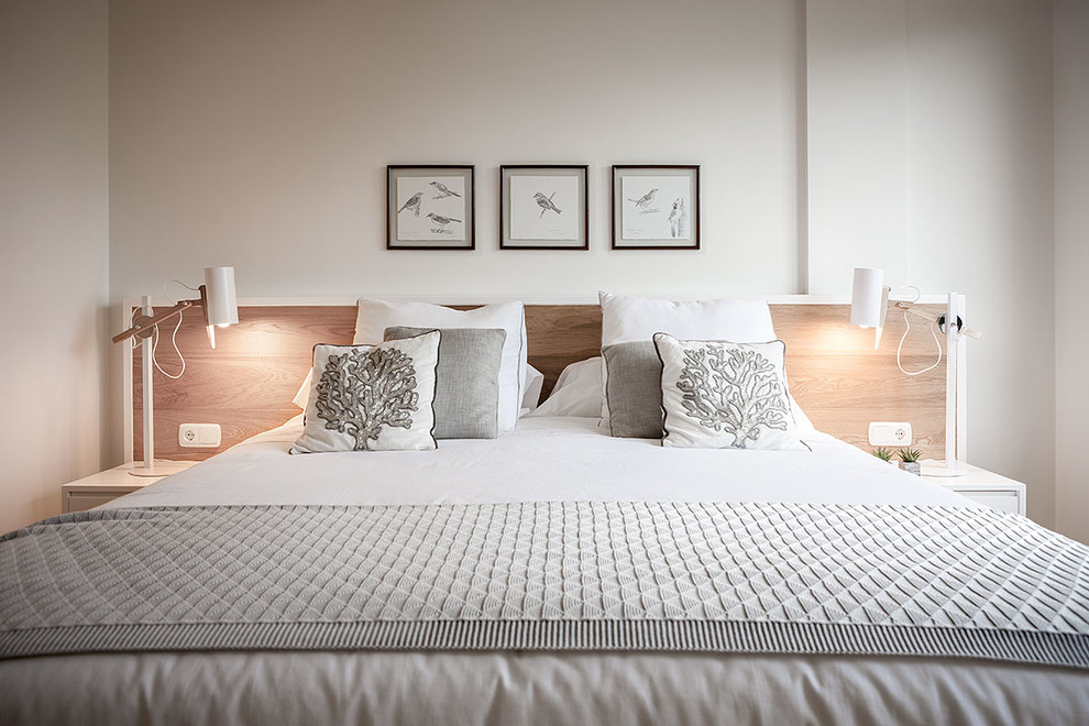 Immagine di una piccola camera matrimoniale minimalista con pareti bianche e parquet chiaro