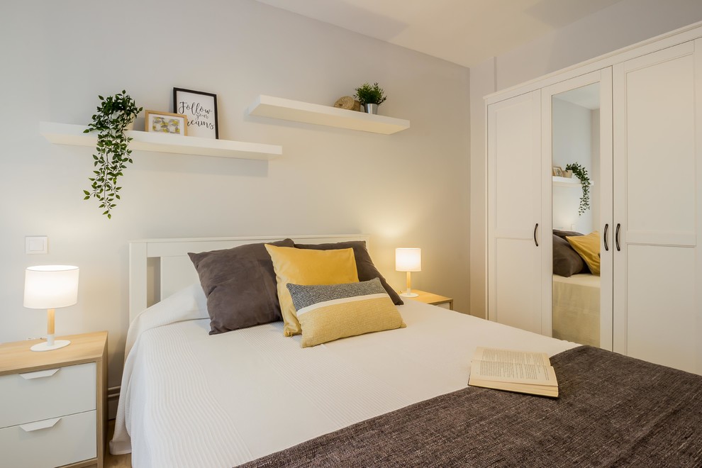 Imagen de dormitorio escandinavo con paredes grises y suelo laminado