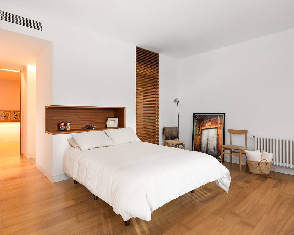 Großes Modernes Hauptschlafzimmer ohne Kamin mit weißer Wandfarbe und braunem Holzboden in Madrid