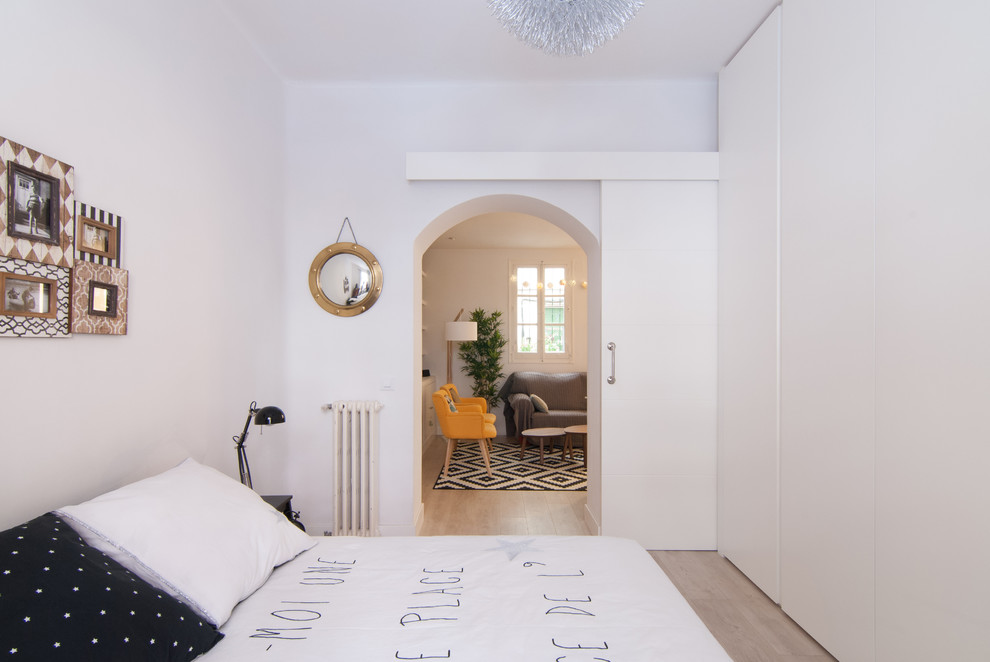 Modelo de dormitorio principal escandinavo de tamaño medio sin chimenea con paredes blancas, suelo de madera clara y suelo beige