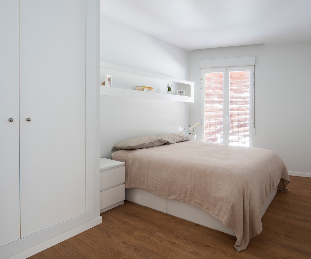 Immagine di una camera da letto contemporanea con pareti bianche, pavimento in legno massello medio e pavimento marrone