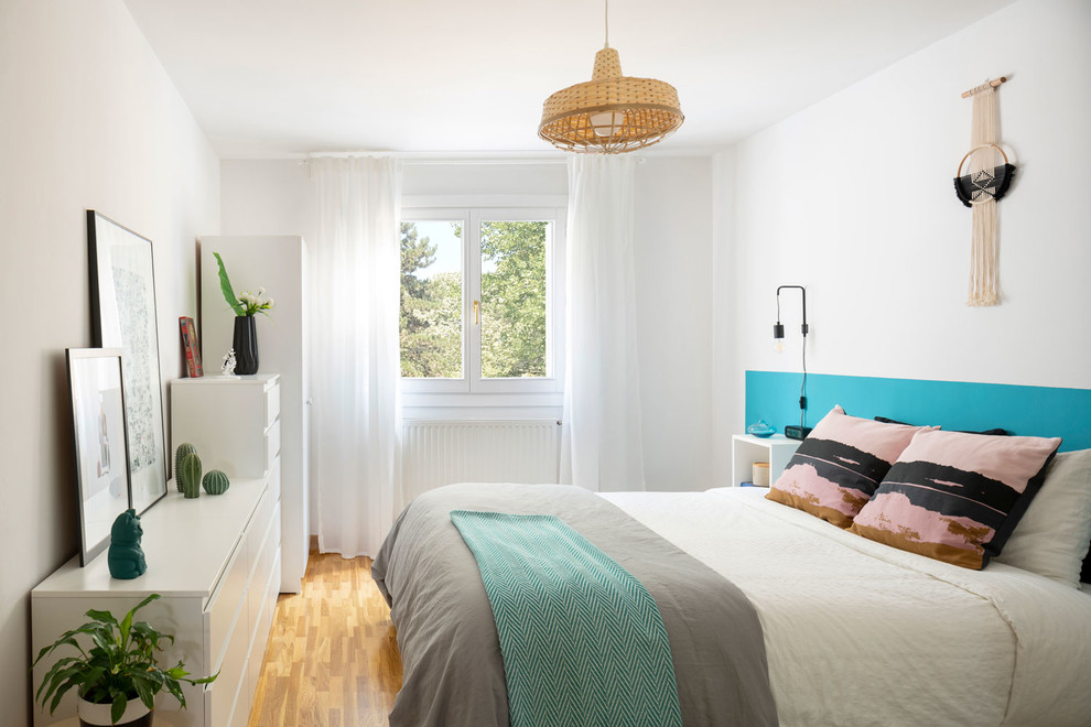 Idée de décoration pour une chambre parentale nordique de taille moyenne avec un sol en bois brun, un sol marron et un mur blanc.