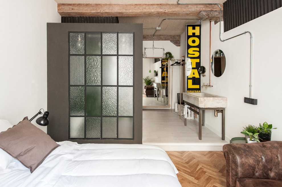 Inspiration för mellanstora industriella sovrum, med vita väggar och mellanmörkt trägolv