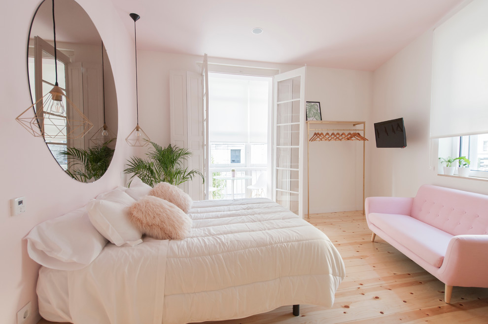 Ejemplo de dormitorio tipo loft escandinavo de tamaño medio con paredes multicolor y suelo de madera clara