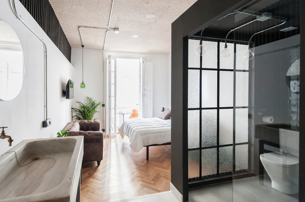 Modelo de dormitorio industrial de tamaño medio sin chimenea con paredes blancas y suelo de madera en tonos medios