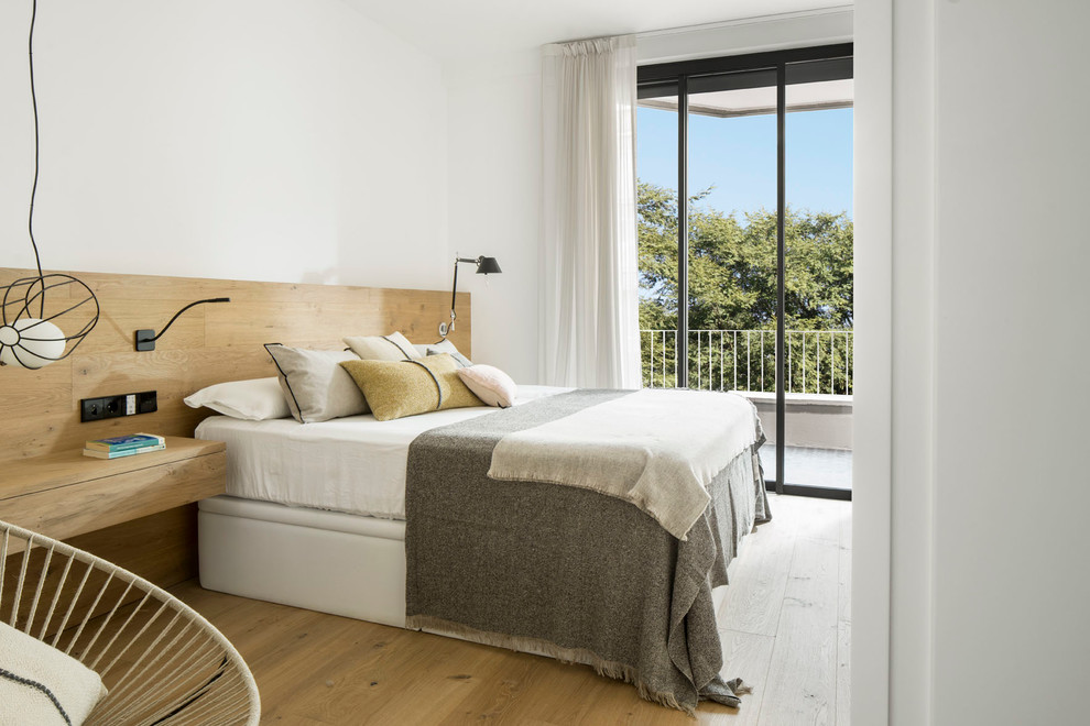 Mittelgroßes Modernes Hauptschlafzimmer ohne Kamin mit weißer Wandfarbe und braunem Holzboden in Barcelona