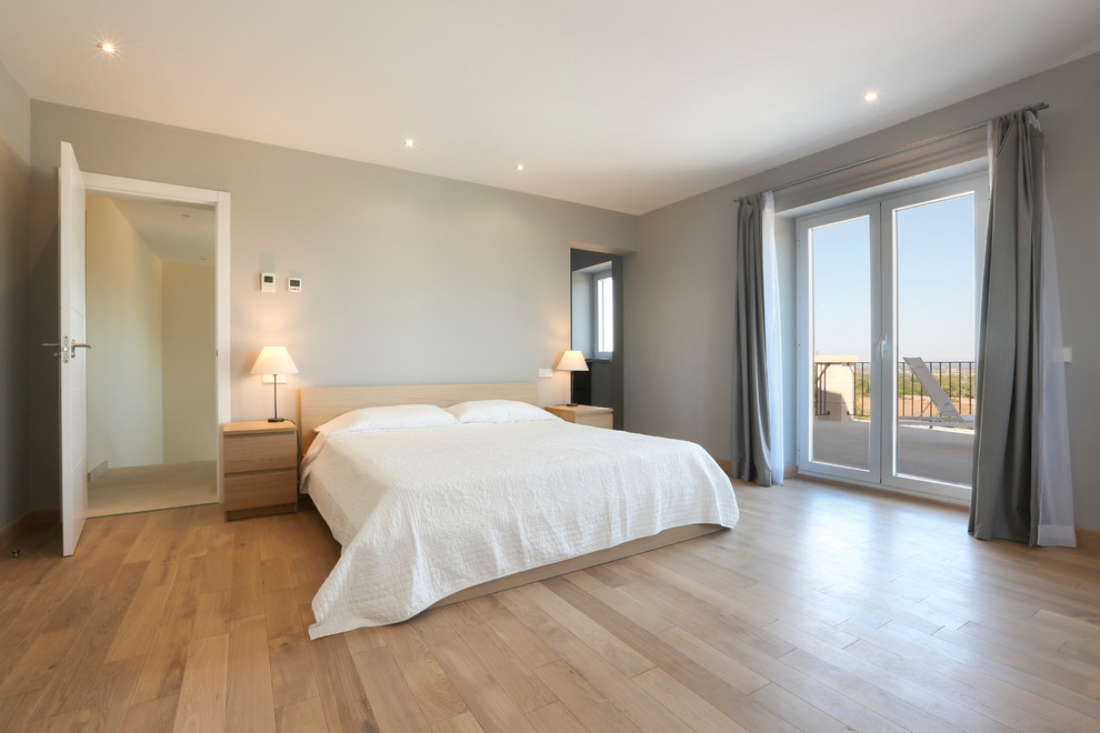 Diseño de dormitorio principal escandinavo de tamaño medio sin chimenea con paredes grises y suelo de madera en tonos medios