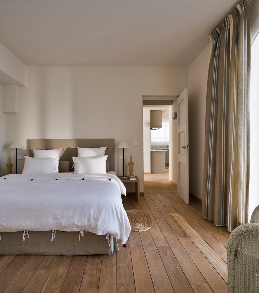 Diseño de dormitorio principal mediterráneo de tamaño medio sin chimenea con paredes blancas y suelo de madera en tonos medios