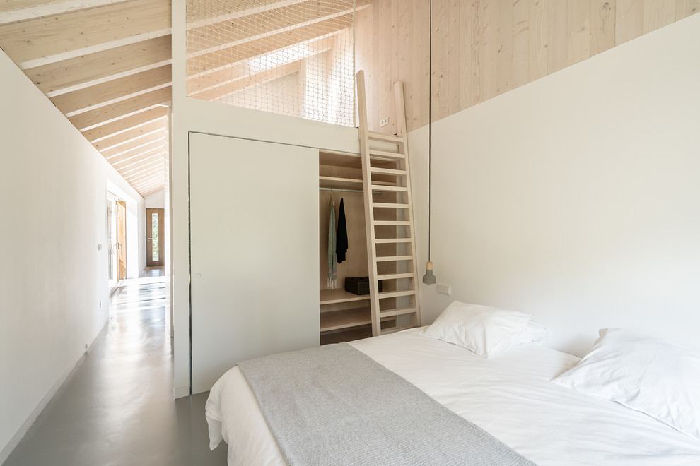 Imagen de dormitorio principal escandinavo de tamaño medio sin chimenea con paredes blancas, suelo de cemento y suelo gris