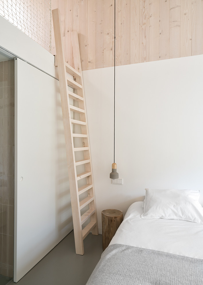 Modelo de dormitorio principal nórdico de tamaño medio sin chimenea con paredes blancas, suelo de cemento y suelo gris